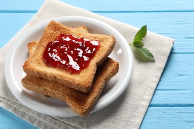 Açık mavi ahşap masada reçelli leziz tostlar, yakın plan.