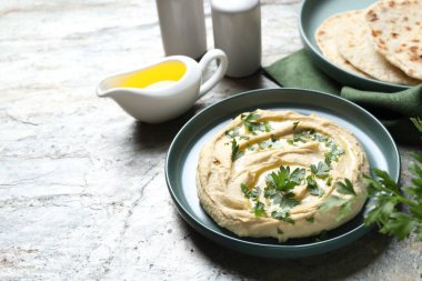 Zeytinyağı ve maydanozlu lezzetli humus. Gri desenli masa, yazı için yer.