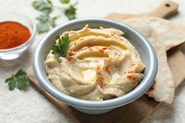 Zeytinyağı, maydanoz ve biberli leziz humus beyaz masada, yakın plan.