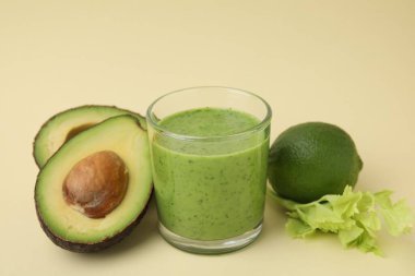 Lezzetli yeşil smoothie cam ve bej arka planda ürünler, yakın plan