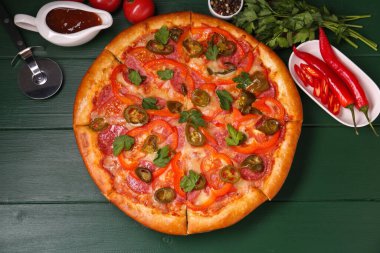 Lezzetli pizza Diablo, malzemeler ve keski yeşil ahşap masa, düz uzanma