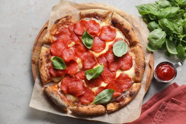 Açık gri masada fesleğenli ve soslu lezzetli biberli pizza.