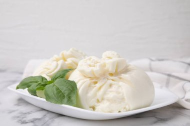 Beyaz mermer masada nefis burrata peyniri ve fesleğen, yakın plan.