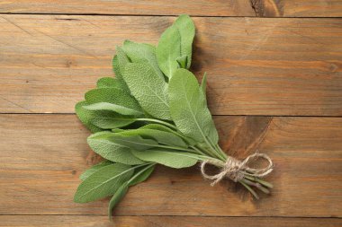 Ahşap masanın üstünde yeşil adaçayı yaprakları var.