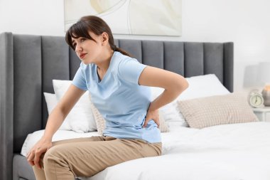 Evde sırt ağrısı çeken üzgün bir kadın.