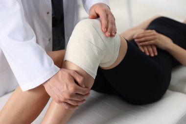 Spor sakatlığı. Hastanede hastanın dizini muayene eden doktor, yakın plan.