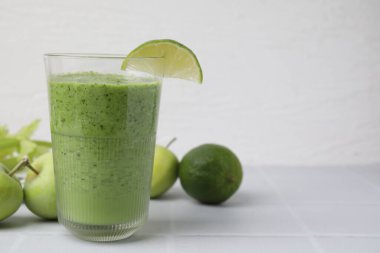 Lezzetli yeşil smoothie, limonlu ve elmalı, beyaz fayanslı masa, yakın plan. Metin için boşluk