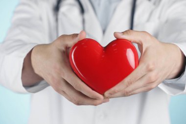 Açık mavi arka planda kırmızı kalpli doktor, seçici odaklanma