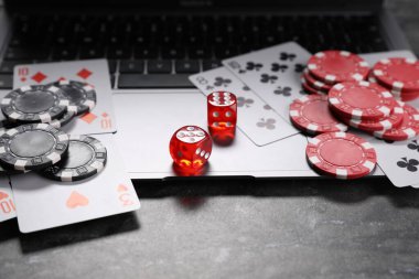 Poker fişleri, dizüstü bilgisayar, kumar kartları ve kumar kağıtları gri masada. Çevrimiçi oyun