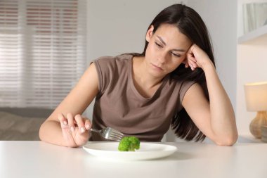 Yeme bozukluğu. Brokoli yanında çatal tutan üzgün kadın.