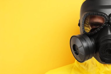 Sarı arka planda gaz maskeli bir işçi, yakın plan. Metin için boşluk