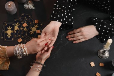 Falcı, siyah masada kadının avucundaki çizgileri okuyor. Chiromancy