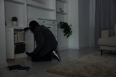 Hırsız yabancı evdeki çekmecelerde para arıyor. Hırsızlık.