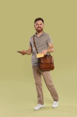 Kahverengi çantalı postacı açık yeşil arka planda mektuplar getiriyor.