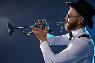 Profesyonel müzisyen karanlık arka planda dumanla trompet çalıyor.