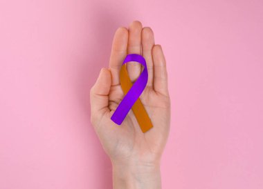 Dünya Sedef Hastalığı Günü. Pembe arka planda destek sembolü olarak turuncu ve orkide kurdeleli kadın.