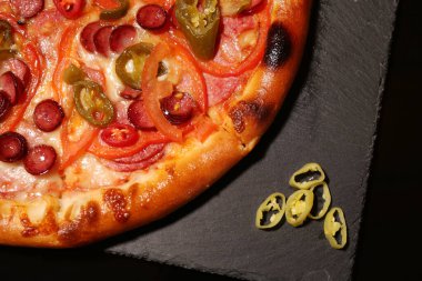 Lezzetli pizza Diablo ve biber tahtada siyah arka planda, üst manzara