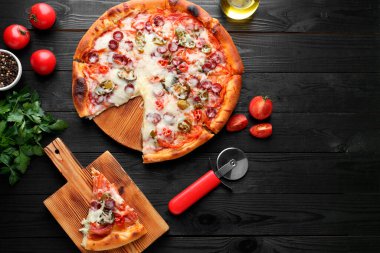 Lezzetli pizza Diablo, ürünler ve siyah ahşap masa, düz yatak. Metin için boşluk