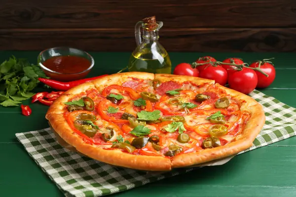 Stock image Delicious pizza Diablo and ingredients on green wooden table