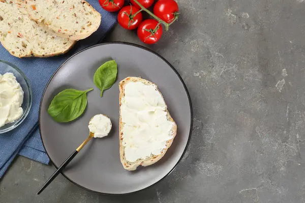 Krem peynirli ekmek parçaları, fesleğen yaprakları ve domatesler gri desenli masa, düz yatak. Metin için boşluk