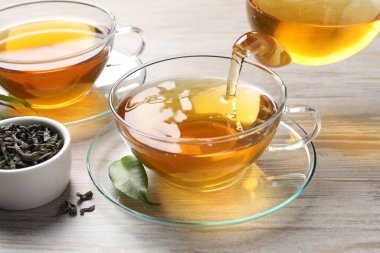 Gri ahşap masada serinletici yeşil çayı fincana dök, kapat.