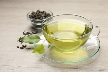 Yeşil çayı fincanda tazeleyen ve ahşap masada yapraklar, yakın plan