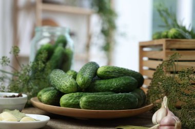 Taze salatalıklar, ahşap masada dereotu ve baharatlar, yakın plan. Turşu hazırlama