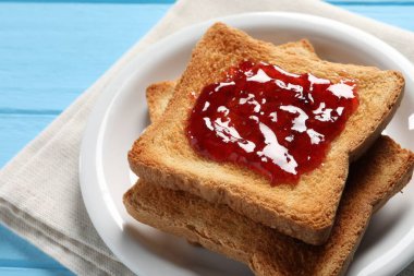 Açık mavi ahşap masada reçelli leziz tostlar, yakın plan.