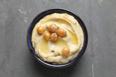 Zeytinyağlı lezzetli humus ve gri desenli masada nohut, üst manzara.