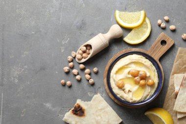 Zeytinyağlı lezzetli humus, nohut, limon ve pide gri desenli masada, düz yerde.