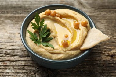 Zeytinyağlı lezzetli humus, nohut ve pide kasede ahşap masada, yakın plan.