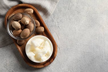 Doğal Shea tereyağı kasede ve fındıklar gri masada, üst manzara. Metin için boşluk