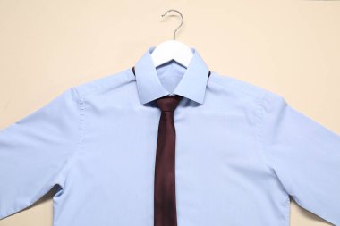 Bej arka planda gömlek ve kravat askısı, üst görünüm