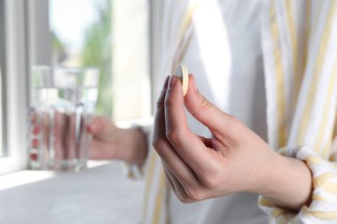 İçerideki su bardağına coşkulu haplar koyan kadın, yakın plan.