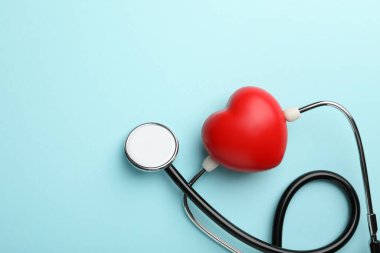 Stetoskop ve açık mavi arka planda kırmızı kalp, üst manzara. Metin için boşluk