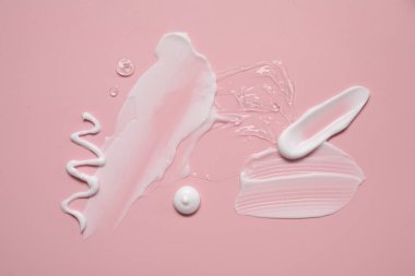 Pembe arka planda yüz kremi ve jöle, üst manzara.