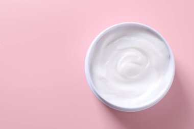 Pembe arka planda kavanozda yüz kremi, üst manzara. Metin için boşluk