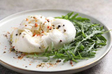 Lezzetli burrata peyniri, roka ve baharatlar masada, yakın plan.