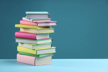 Açık mavi arkaplan üzerine renkli kitap yığını, metin için boşluk