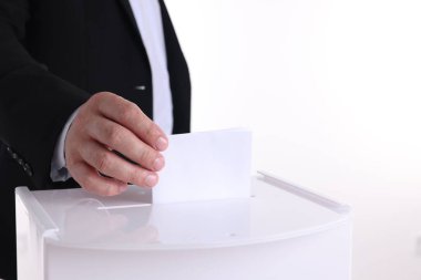 Beyaz arka plana karşı oy sandığına oy veren adam, yakın plan.