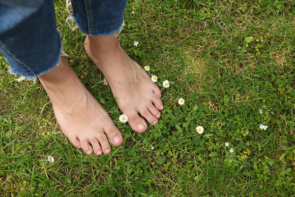 Woman walking barefoot on green grass outdoors, top view. Space for text