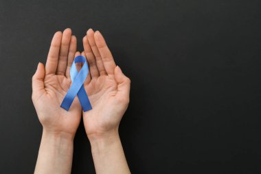 Siyah arka planda mavi farkındalık kurdelesi olan bir kadın. Metin için boşluk