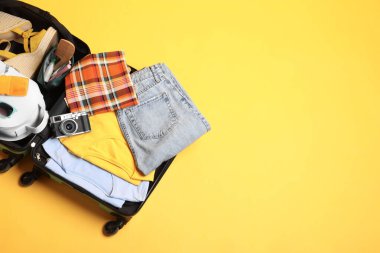 Sarı arka planda gezginlerin eşyalarının olduğu valizi aç. Metin için boşluk