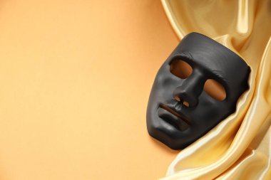 Tiyatro sanatları. Soluk turuncu arka planda siyah maske ve altın kumaş, üst manzara. Metin için boşluk