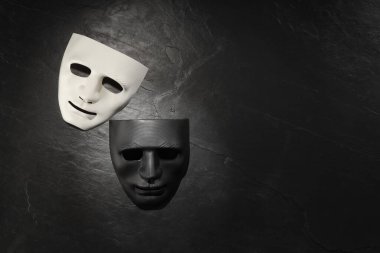 Siyah tahta yüzeyde plastik yüz maskeleri, yazı için üst görünüm ve boşluk. Tiyatro performansı