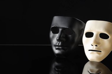 Siyah ayna yüzeyinde plastik yüz maskeleri, metin için boşluk. Tiyatro performansı