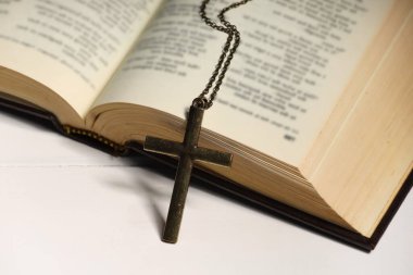 Beyaz ahşap masada zincir ve İncil 'le yan yana, yakın plan. Hıristiyanlık Dini