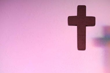 Wooden cross on pink textured background, space for text. Religion of Christianity clipart