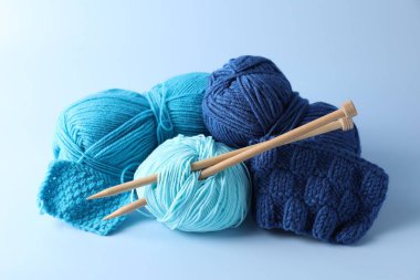 Hafif arkaplanda farklı iplikler, örgü iğneleri ve desenler var.
