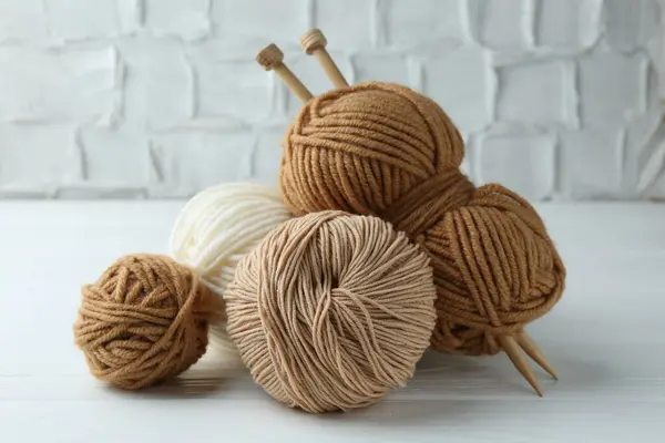 stock image Skeins of different yarn and knitting needles on white wooden table, closeup